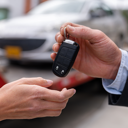 Male hand giving car key to female hand.